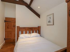 A bedroom with a bed and wooden door at Beudy'r Wennol in Groeslon