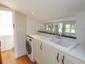 A utility room with a washing machine and sink at Beudy'r Wennol in Groeslon