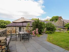 An outdoor patio with a table and chairs at Beudy'r Wennol in Groeslon