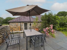 An outdoor seating area with a table and chairs at Beudy'r Wennol Groeslon