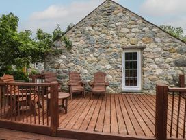 An outdoor area with a wooden deck and chairs at Beudy'r Wennol Groeslon