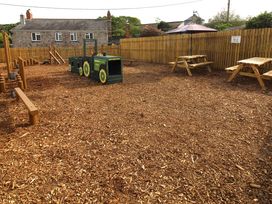 An outdoor play area with a tractor play structure and picnic tables at Hazel Lodge Lanivet near Bodmin