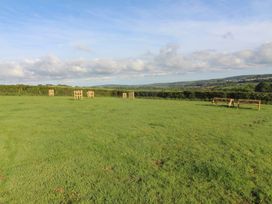 An outdoor area with wooden benches and hills in the background at Cedar Lodge in Lanivet near Bodmin