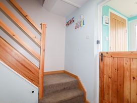 A staircase with carpeted steps wooden railing and a wooden gate next to a wooden door at Daisy Cottage in Perranporth
