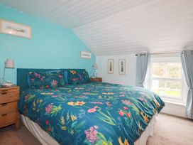 A bedroom with a floral bedspread on a bed and two wooden bedside tables with lamps at Daisy Cottage in Perranporth