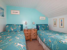 A bedroom with two single beds with animal patterned bedding bedside tables lamps and framed pictures on walls at Daisy Cottage in Perranporth