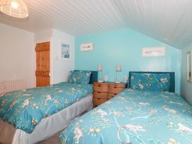 A bedroom with two single beds with patterned bedding and a wooden door at Daisy Cottage in Perranporth