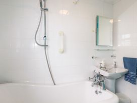 A bathroom with a bathtub shower sink mirror and a blue towel at Daisy Cottage in Perranporth