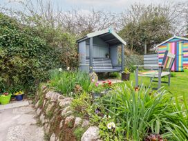 A garden with a covered bench chair colorful shed and various plants at Daisy Cottage in Perranporth