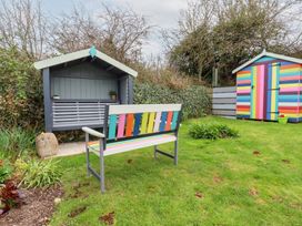 A garden with a colorful bench a striped shed and a covered wooden seat at Daisy Cottage in Perranporth