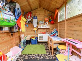 A wooden playroom with toys a toy kitchen a pink keyboard and a small table with chairs at Daisy Cottage in Perranporth