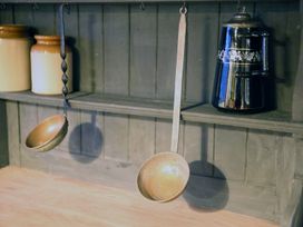A kitchen shelf with ceramic jars metal ladles and a black jug at Pant Dafydd Goch in Llangollen