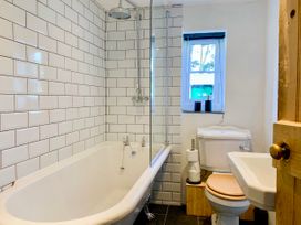 A bathroom with a bathtub shower combination toilet with wooden seat and a sink at Pant Dafydd Goch in Llangollen