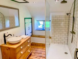 A bathroom with a wooden dresser sink mirror shower and small window at Pant Dafydd Goch in Llangollen