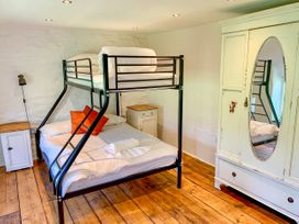 A bedroom with a bunk bed a wardrobe with a mirror and wooden floors at Pant Dafydd Goch in Llangollen