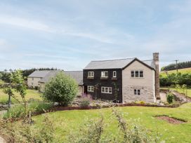 A stone and wood house with a garden and lawn in a rural setting at Pant Dafydd Goch in Llangollen