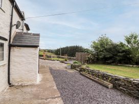 Exterior view of a stone house with patio and garden area with stone wall and trees at Pant Dafydd Goch in Llangollen