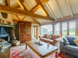 A living room with wooden beams a fireplace sofas a wooden coffee table and large windows overlooking a garden at Pant Dafydd Goch in Llangollen