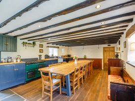 A kitchen with a long wooden dining table and multiple chairs at Pant Dafydd Goch in Llangollen
