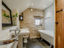 A bathroom with a pedestal sink a toilet and a clawfoot bathtub with a glass shower screen at Pant Dafydd Goch in Llangollen