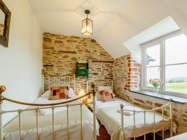A bedroom with two single beds and a window with flowers on the sill at Pant Dafydd Goch in Llangollen