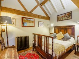 A bedroom with a wooden bed frame pillows a red rug a floor lamp wooden chairs and framed artwork at Pant Dafydd Goch in Llangollen