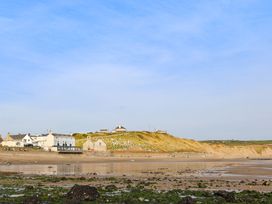 A coastal village with white houses and a cemetery on a hill by the beach at Bryn Ffynnon in Bryncroes near Aberdaron