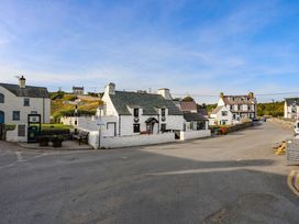 A street with white stone buildings and road signs at Bryn Ffynnon in Bryncroes near Aberdaron