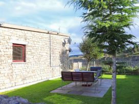 An outdoor area with a stone wall and seating at Boavista in Carnforth