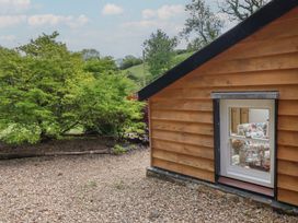 An exterior view of a wooden cabin with a window and garden at Pottery Barn in Branscombe