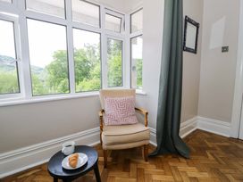 A snug with an armchair and table at Coedfryn in Betws-y-Coed