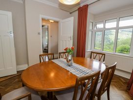 A dining room with a wooden table and chairs at Coedfryn in Betws-y-Coed
