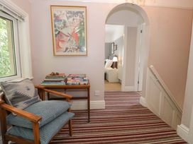 A hallway with a chair, books on a table and an artwork at Coedfryn in Betws-y-Coed