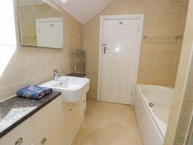 A bathroom with a washbasin and a bath at Coedfryn Betws-y-Coed
