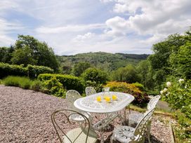 A garden with a table and chairs and beverages at Coedfryn in Betws-y-Coed