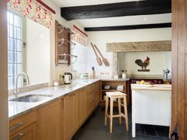 A kitchen with sink, stove, and wooden furniture at Great Bidlake Manor, Bridestowe, near Lydford