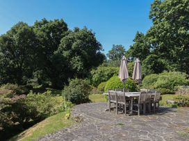 A patio with a table and chairs under umbrellas at Sandsgate, near Spinster's Rock, near Chagford