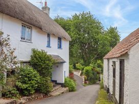A cottage with a thatched roof and shrubs along the pathway at Little Gate Cottage in North Bovey