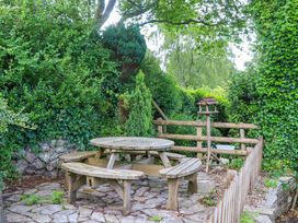 A picnic table with benches in a garden at Little Gate Cottage North Bovey