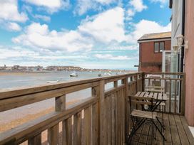 A balcony with wooden table and chairs overlooking the ocean at The Dolphins in Shaldon