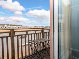 A balcony with a table and chairs overlooking water at The Dolphins in Shaldon