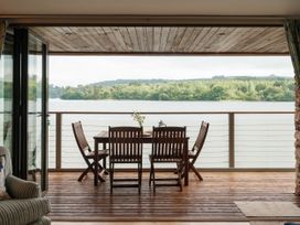 An outdoor dining area with a table and chairs overlooking the river at Sandridge Boathouse Stoke Gabriel
