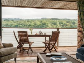 A dining area with a table and chairs overlooking a lake at Sandridge Boathouse Stoke Gabriel