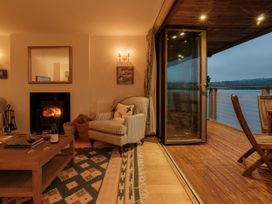A living room with a fireplace and an open door to a deck at Sandridge Boathouse Stoke Gabriel