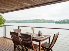 A patio area with a wooden table and chairs overlooking the water at Sandridge Boathouse Stoke Gabriel