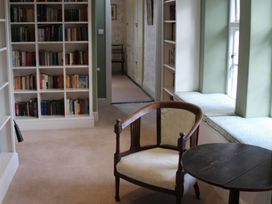 A reading room with a bookshelf and chair at Wootton House Butleigh Wootton, near Compton Dundon