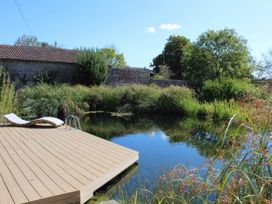 A wooden deck with a pool ladder by a pond at Wootton House Butleigh Wootton near Compton Dundon