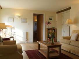 A living room with a sofa, armchair, coffee table, and bookshelf at The Barn in Compton Bishop, near Cheddar