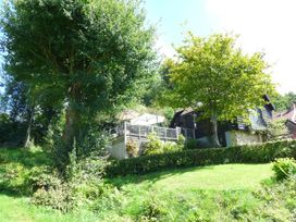 A house with a deck and trees in the garden at Little Evanses in Dalwood, near Axminster