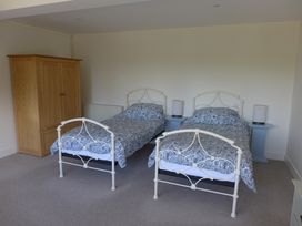 A bedroom with two single beds and a wardrobe at Little Evanses Dalwood near Axminster